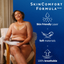 A woman sits in a chair holding a white absorbent pad, with a blue promotional graphic on the right reading 'SkinComfort Formula/MC' and feature icons for skin-friendly layer, soft materials, and 100% breathable.